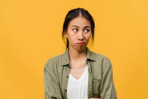 Portrait of young Asia lady with negative expression, excited screaming, crying emotional angry in casual clothing isolated on yellow background with blank copy space. Facial expression concept. photo