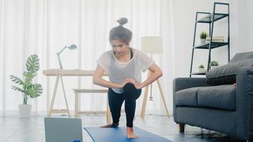 Young Korean lady in sportswear exercises doing working out and using laptop to watching yoga video tutorial at home. Distant training with personal trainer, social distance, online education concept. photo