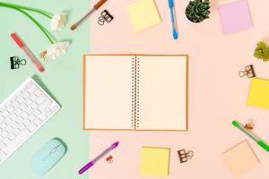 Creative flat lay photo of workspace desk. Top view office desk with keyboard, mouse and open mockup black notebook on pastel green pink color background. Top view mock up with copy space photography.