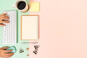 Creative flat lay photo of workspace desk. Top view office desk with keyboard, mouse and open mockup black notebook on pastel green pink color background. Top view mock up with copy space photography.