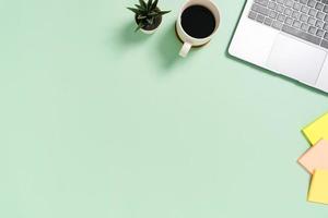 espacio de trabajo mínimo: foto creativa plana del escritorio del espacio de trabajo. Escritorio de oficina de vista superior con laptop y taza de café sobre fondo de color verde pastel. vista superior con espacio de copia, fotografía plana.