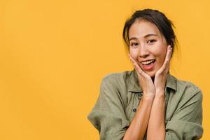 Young Asia lady with positive expression, smile broadly, dressed in casual clothing and looking at camera over yellow background. Happy adorable glad woman rejoices success. Facial expression concept. photo