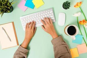 Creative flat lay photo of workspace desk. Top view office desk with keyboard, mouse and open mockup black notebook on pastel green color background. Top view mock up with copy space photography.