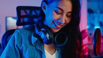Happy asia girl blogger play synthesizer keyboard wear headphone and record music with sound mixer on laptop in living room home studio at night. Music content creator, tutorial, Broadcast concept. photo