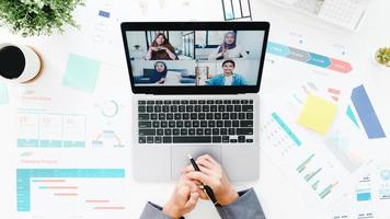 Top view of young Asia businesswoman using laptop talk to colleague about plan in video call meeting while work from home at living room. Social distancing, quarantine for corona virus prevention. photo