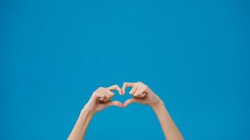 Young woman hand shows making shape of heart sending love to her lover over blue background. Copy space for place a text, message for advertisement. Advertising area, mockup promotional content. photo