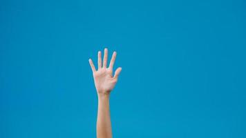 Young woman waving saying greeting, goodbye making hand gestures isolated over blue background. Copy space for place a text, message for advertisement. Advertising area, mock up promotional content. photo