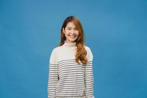 Young Asia lady with positive expression, smile broadly, dressed in casual clothing and looking at camera over blue background. Happy adorable glad woman rejoices success. Facial expression concept. photo