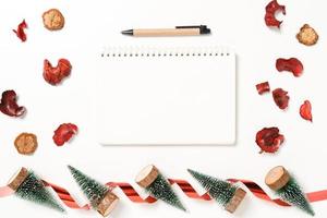 Minimal creative flat lay of winter christmas traditional composition and new year holiday season. Top view open mockup black notebook for text on white background. Mock up and copy space photography. photo