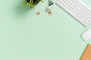 Minimal work space - Creative flat lay photo of workspace desk. Top view office desk with keyboard, mouse and book on pastel green color background. Top view with copy space, flat lay photography.