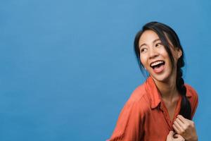 Portrait of young Asia lady with positive expression, smile broadly, dressed in casual clothing over blue background. Happy adorable glad woman rejoices success. Facial expression concept. photo