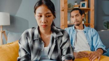 Upset asian couple wife sit on couch listen to furious husband yelling feel unhappy talk negative to her. Couple have fight or disagreement at home, Couple problem, family married toxic relationship. photo