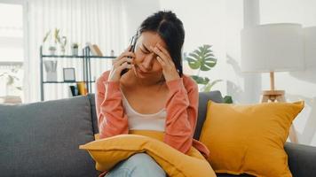 señorita sentada en el sofá hablar con un amigo y recibir malas noticias en casa. relación de larga distancia, mala relación, problema de trabajo, relación rota, mantener la distancia, concepto de cuarentena de covid. foto