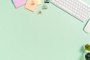 espacio de trabajo mínimo: foto creativa plana del escritorio del espacio de trabajo. escritorio de oficina de vista superior con teclado, mouse y libro sobre fondo de color verde pastel. vista superior con espacio de copia, fotografía plana.