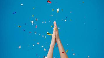 Young girl show hand clapping applause under confetti rain and celebrating over blue background. Copy space for place a text, message for advertisement. Advertising area, mock up promotional content. photo