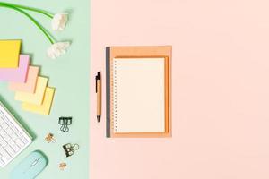 Creative flat lay photo of workspace desk. Top view office desk with keyboard, mouse and open mockup black notebook on pastel green pink color background. Top view mock up with copy space photography.