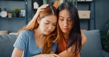 Asian women teenager embracing to calm her sad best friends from feeling down from breakup with boyfriend in living room at home. Friendship counseling and care, unhappy girl support her girlfriend. photo