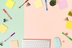 Minimal work space - Creative flat lay photo of workspace desk. Top view office desk with keyboard, mouse and adhesive note on pastel green pink color background. Top view with copy space photography.