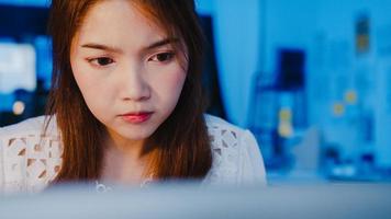 mujeres asiáticas independientes que usan una computadora portátil trabajan duro en la nueva oficina en casa normal. trabajando desde la sobrecarga de la casa por la noche, trabajo a distancia, autoaislamiento, distanciamiento social, cuarentena para la prevención del virus corona.