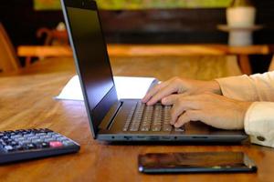 Man hand working on laptop computer on table and home quarantine, new normal photo