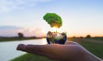 globo de la naturaleza en la mano con la salida del sol foto