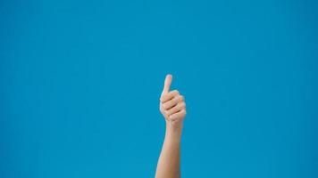 Young woman hand showing thumb up sign with fingers isolated over blue background in studio. Copy space for place a text, message for advertisement. Advertising area, mock up promotional content. photo