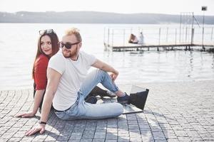 Dos estudiantes, chico y chica, están sentados al aire libre y disfrutando de una computadora portátil, estudiando al aire libre en un día soleado foto