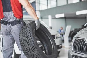 Mechanic holding a tire tire at the repair garage. replacement of winter and summer tires. photo