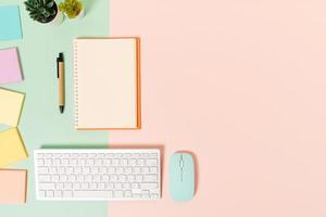 Creative flat lay photo of workspace desk. Top view office desk with keyboard, mouse and open mockup black notebook on pastel green pink color background. Top view mock up with copy space photography.
