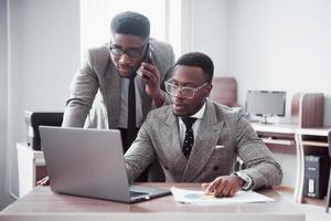 Modern businessman at work. Two confident business people in formalwear discussing something and look at the laptop monitor photo