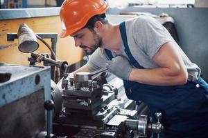 operador experimentado con casco. Concepto de la industria metalmecánica ingeniero profesional obrero metalúrgico operativo fresadora cnc centro en taller de fabricación foto