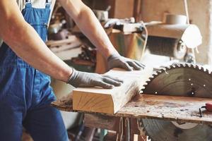 A man works in a joiner's shop, working with a tree. photo