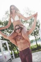 A man holds a woman on his shoulders, they are playful and romantic and smile. photo