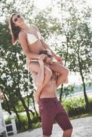 un hombre sostiene a una mujer sobre sus hombros, son juguetones y románticos y sonríen. foto