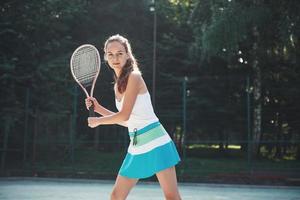 Una mujer bonita vistiendo una cancha de tenis de ropa deportiva en la cancha foto