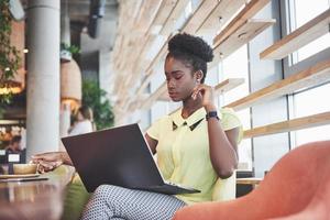 Beautiful young woman sitting in a cafe and working on a laptop photo