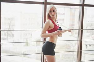 Photo of attractive fitness woman in gym holding bottle of water