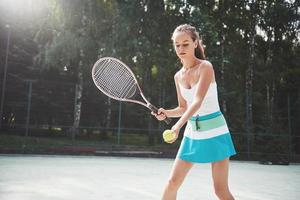 mujer en ropa deportiva sirve pelota de tenis. foto