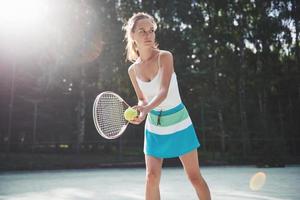 Una mujer bonita vistiendo una cancha de tenis de ropa deportiva en la cancha foto