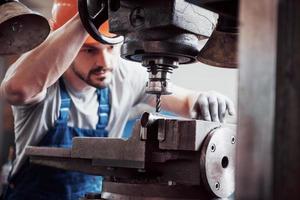 Experienced operator in a hard hat. Metalworking industry concept professional engineer metalworker operating CNC milling machine center in manufacturing workshop photo