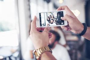 Blur portrait of blissful young best friends with hands holding phone on foreground photo