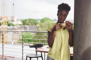 Beautiful young African American business woman drinking coffee at a cafe. Beautiful cozy place photo