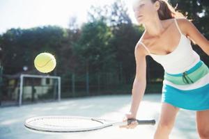 Una mujer bonita vistiendo una cancha de tenis de ropa deportiva en la cancha foto