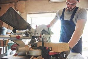 Master in a work suit using a grinder on a sawmill. photo