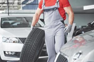 Mechanic holding a tire tire at the repair garage. replacement of winter and summer tires. photo