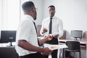 Discussing a project. Two black business people in formalwear discussing something while one of them pointing a paper photo