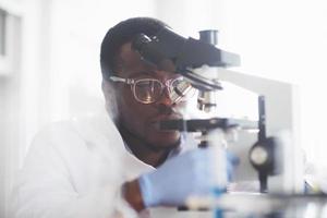 The scientist works with a microscope in a laboratory conducting experiments and formulas. photo