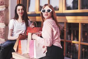 Two women talking after shopping on the street near the window photo