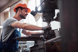 Experienced operator in a hard hat. Metalworking industry concept professional engineer metalworker operating CNC milling machine center in manufacturing workshop photo