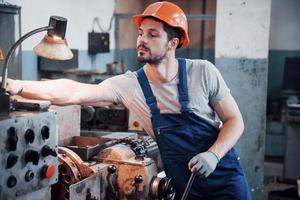 Experienced operator in a hard hat. Metalworking industry concept professional engineer metalworker operating CNC milling machine center in manufacturing workshop photo